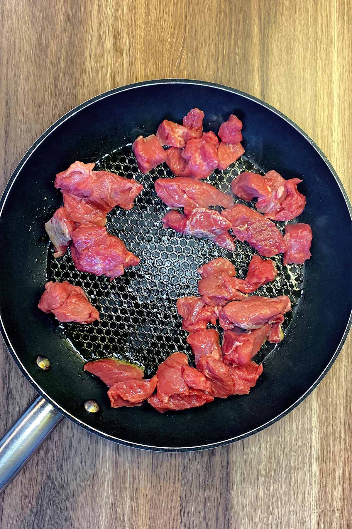 Chunks of beef in a frying pan.