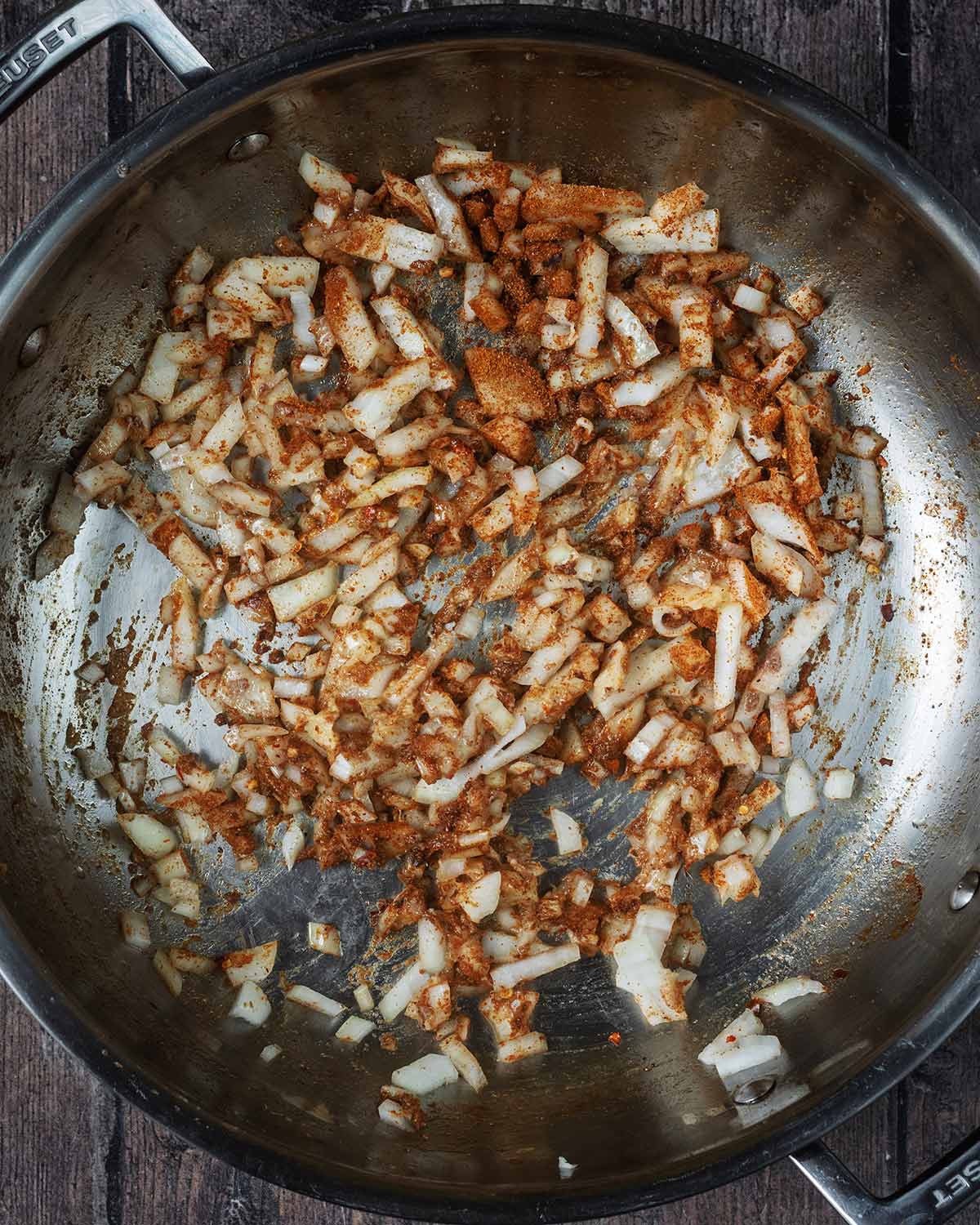 Onions and curry spices cooking in a large pan.