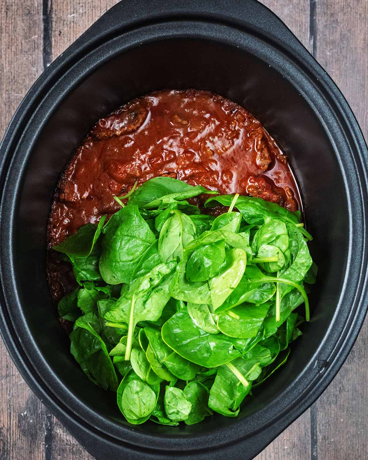 Spinach added to the curry in the slow cooker.