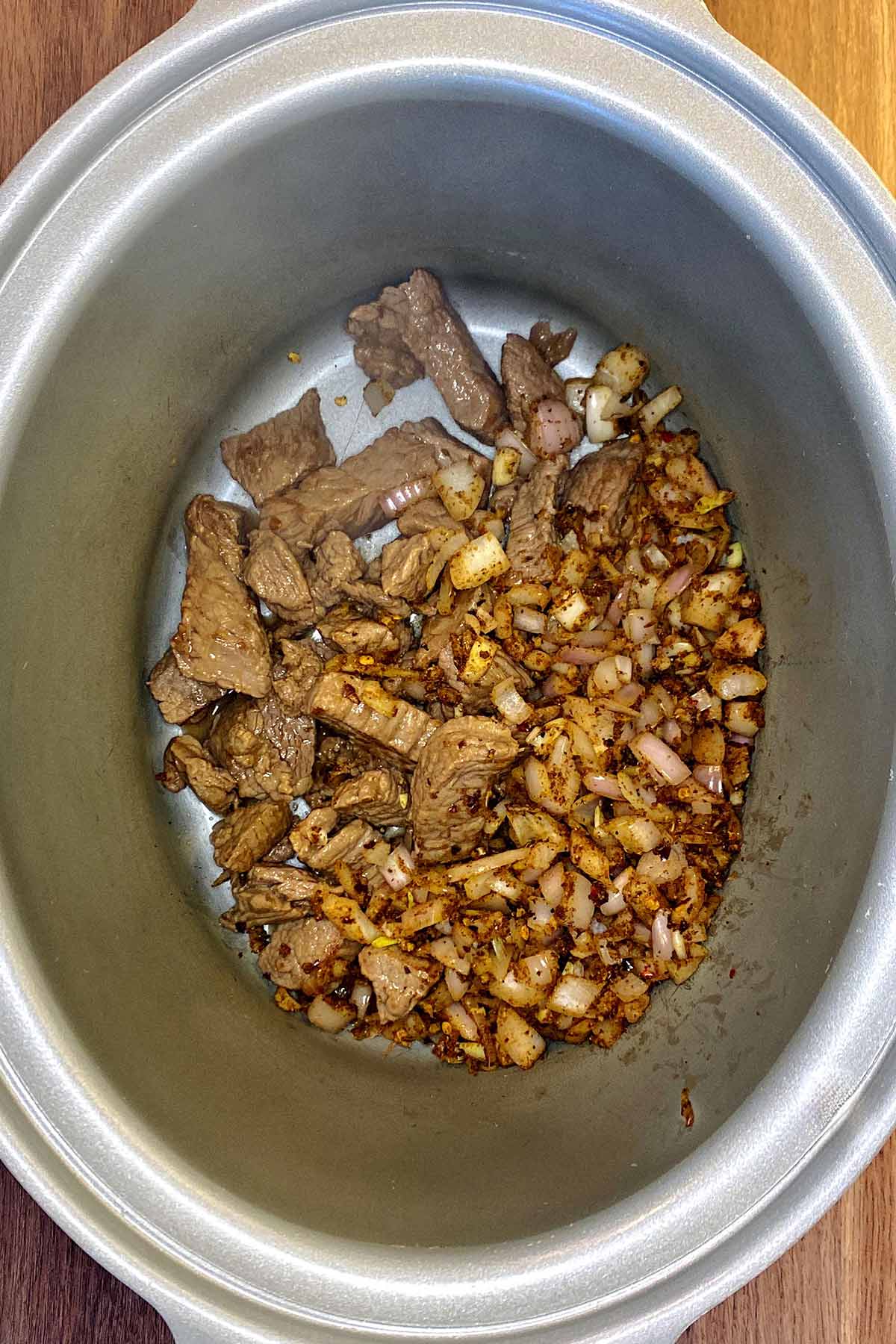 The spiced shallots added to the beef in the slow cooker.