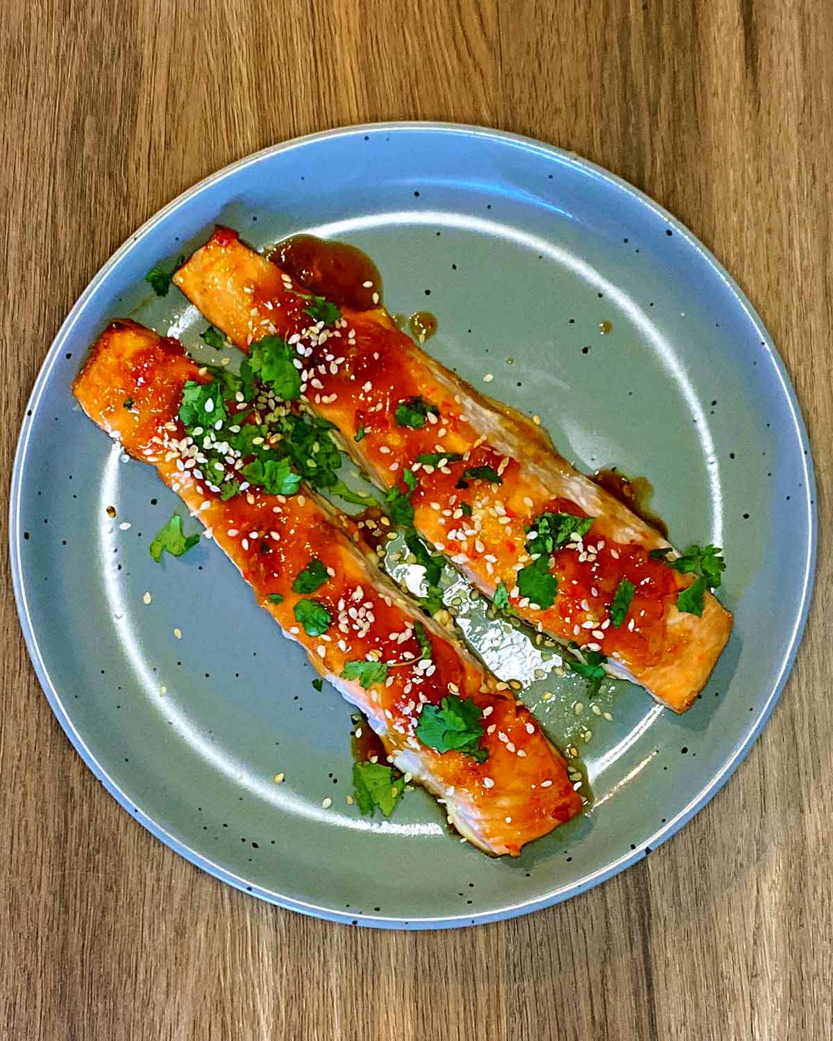 Cooked salmon fillets topped with chopped coriander and sesame seeds.