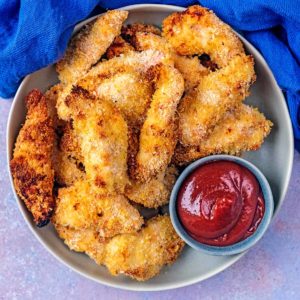 Crispy Chicken Goujons on a plate with a small pot of ketchup.