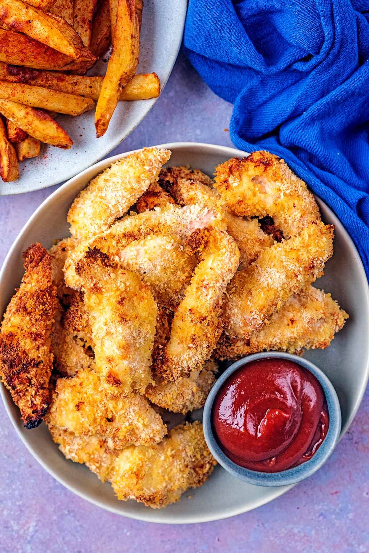 Chicken goujons on a plate with a pot of ketchup.
