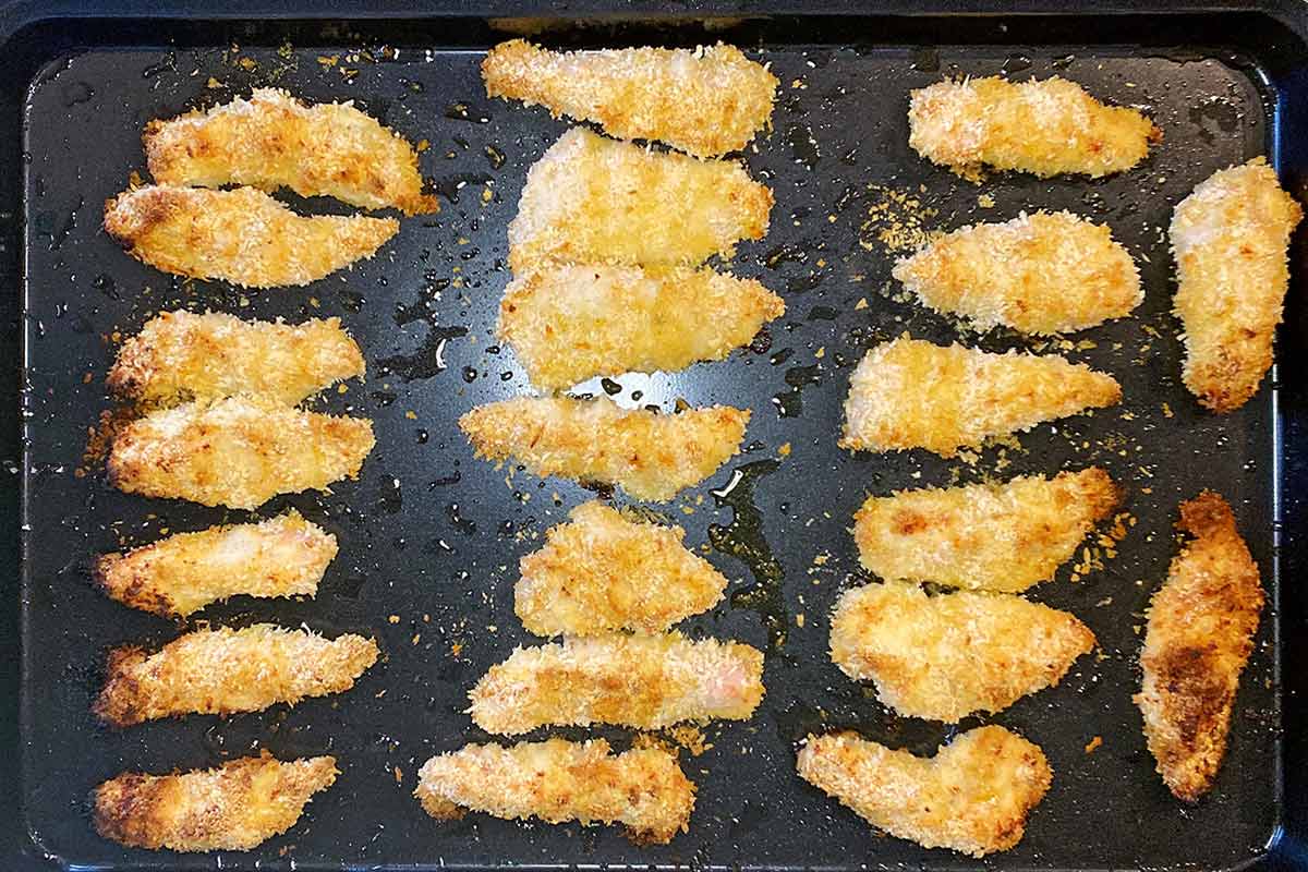 Cooked chicken goujons on a baking tray.