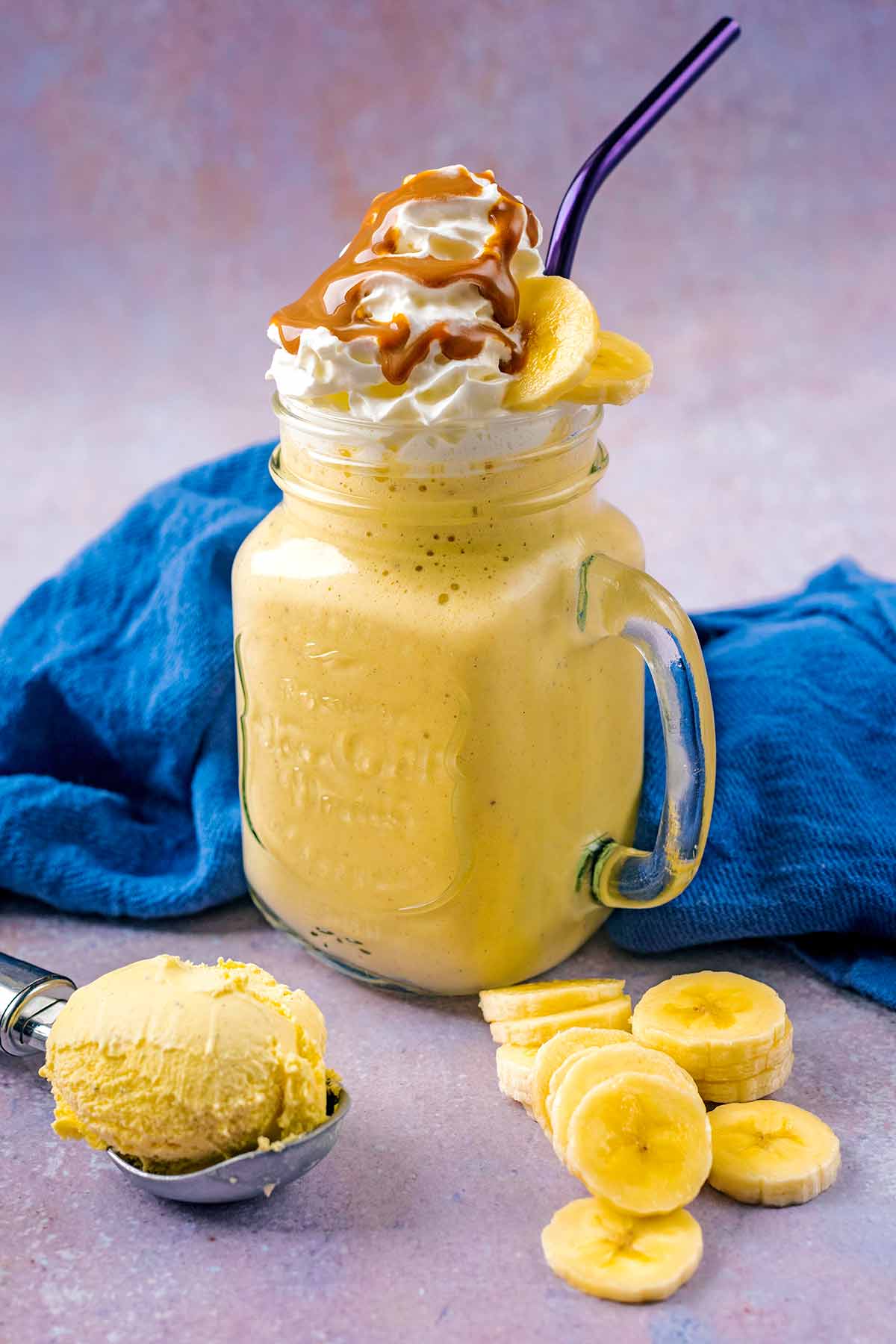 A mason jar full of milkshake topped with cream and sauce.