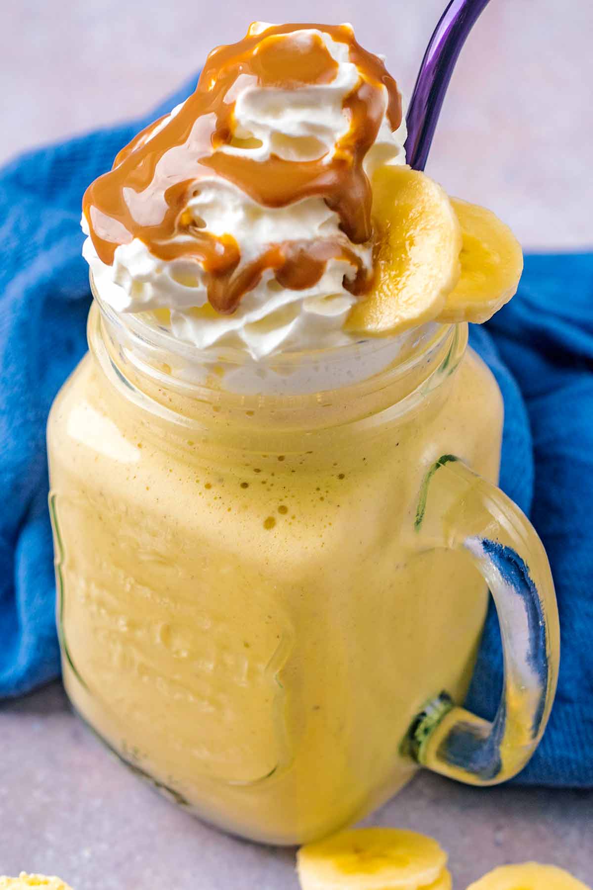 Banana milkshake topped with cream and sliced banana.