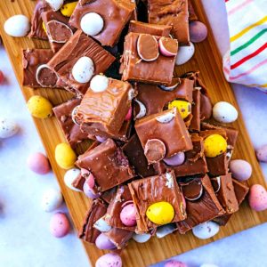 Cubes of mini egg fudge on a wooden board.