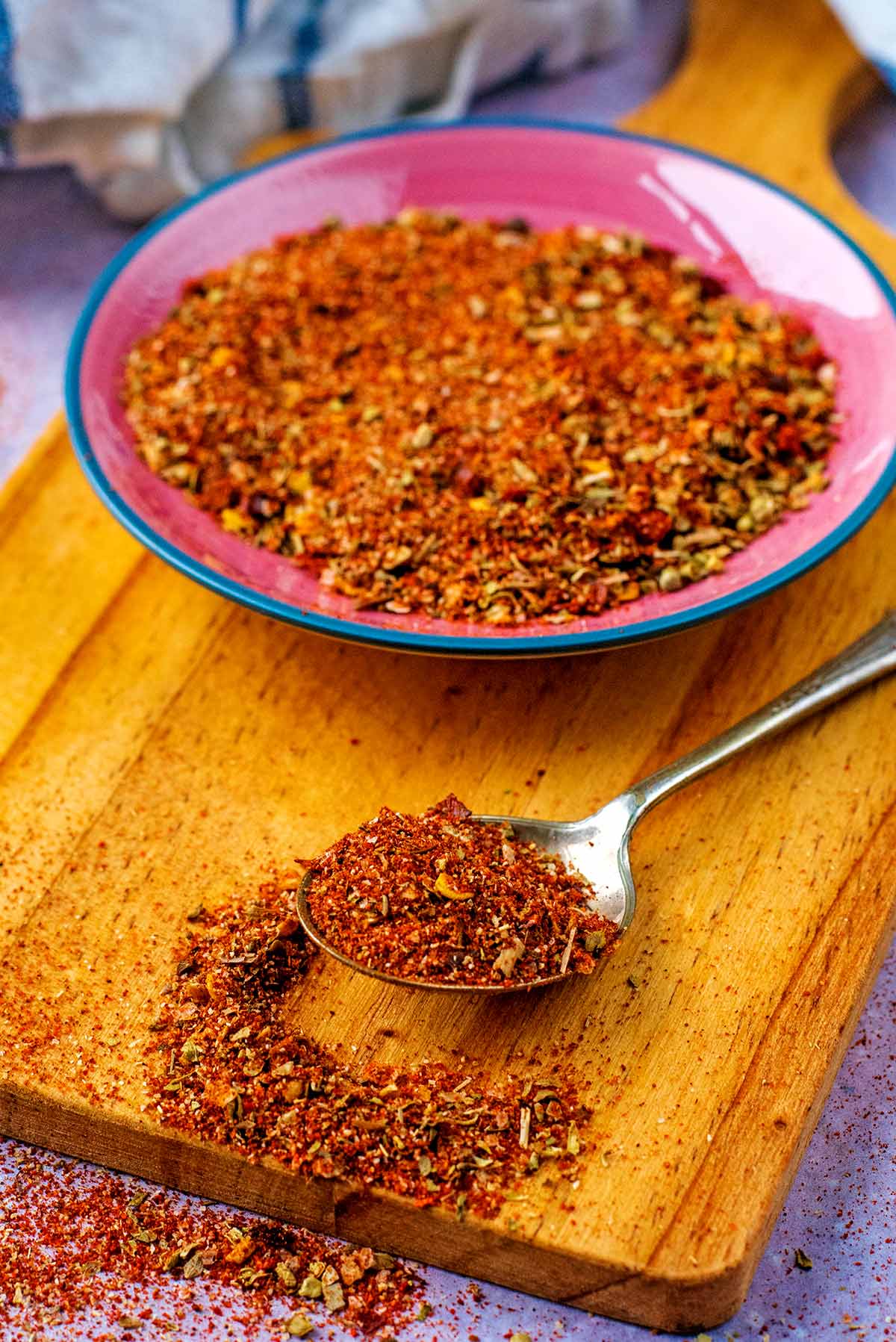 A spoonful of seasoning in front of a dish of the same seasoning.