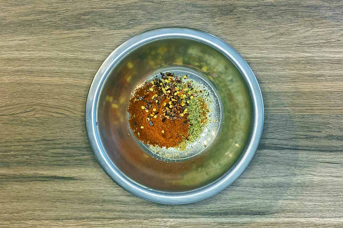 A small mixing bowl with various herbs and spices in it.