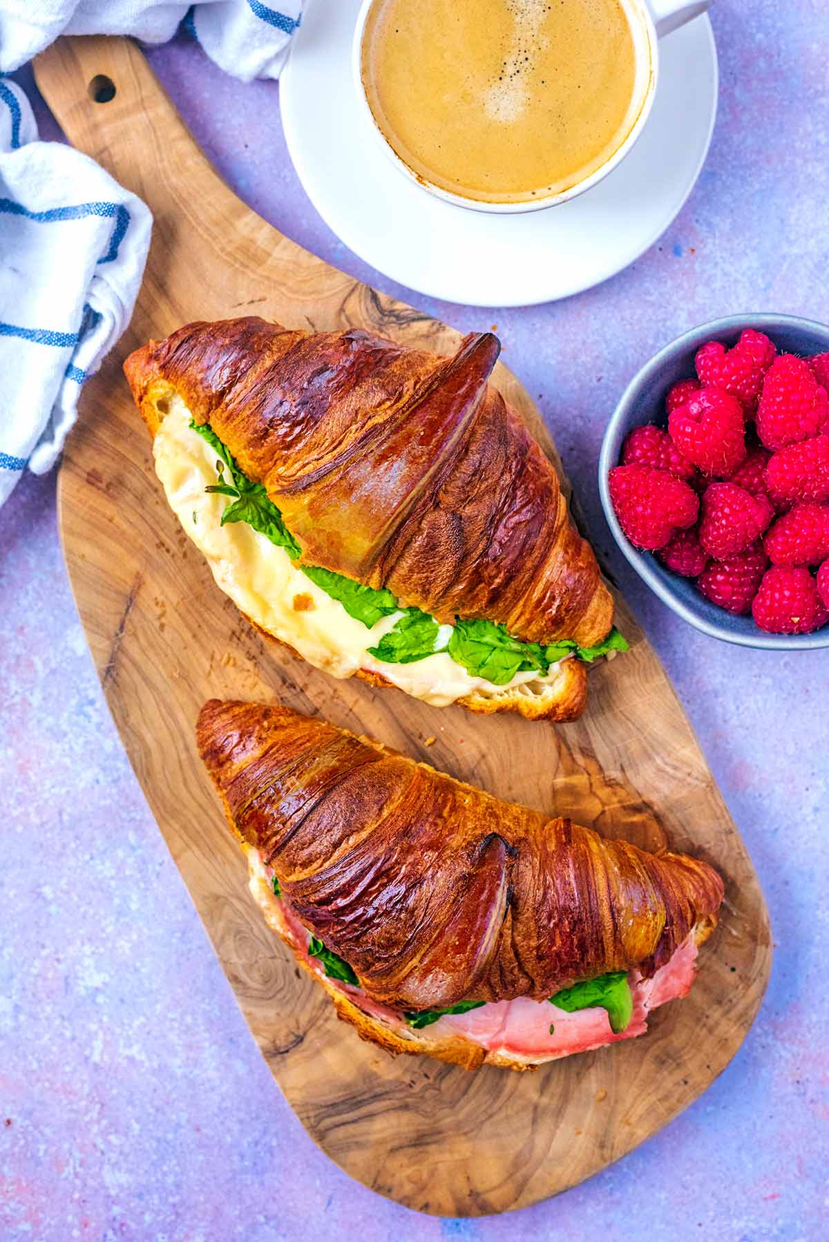 Two stuffed croissants on a wooden serving board.