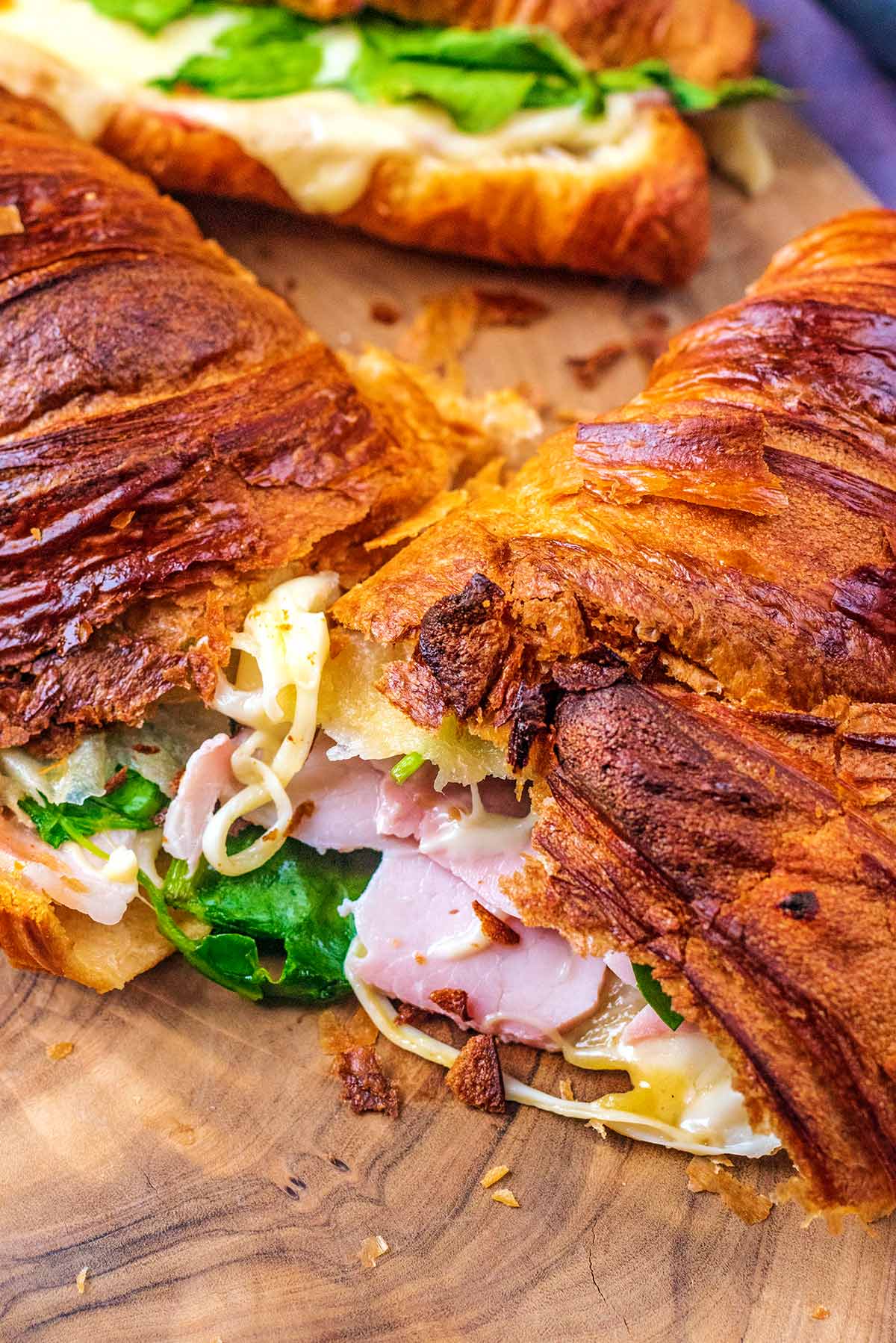 A stuffed croissant cut in half showing ham and cheese inside.
