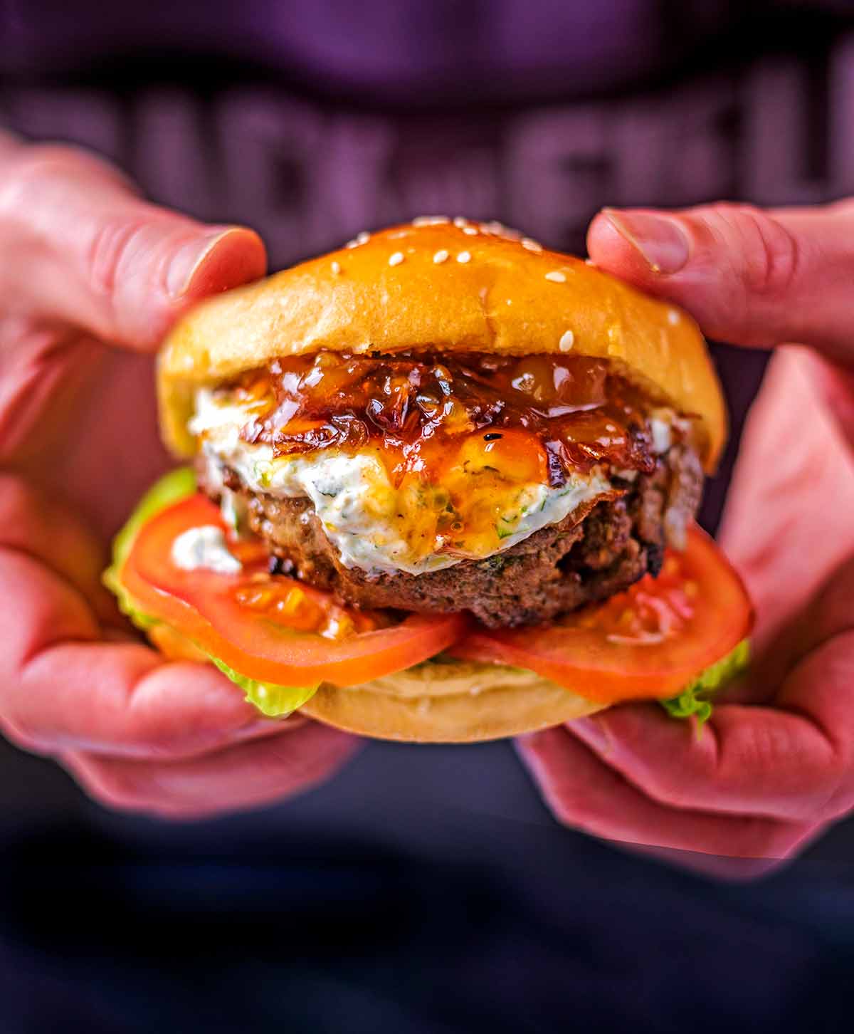 Two hands holding a burger in a bun.