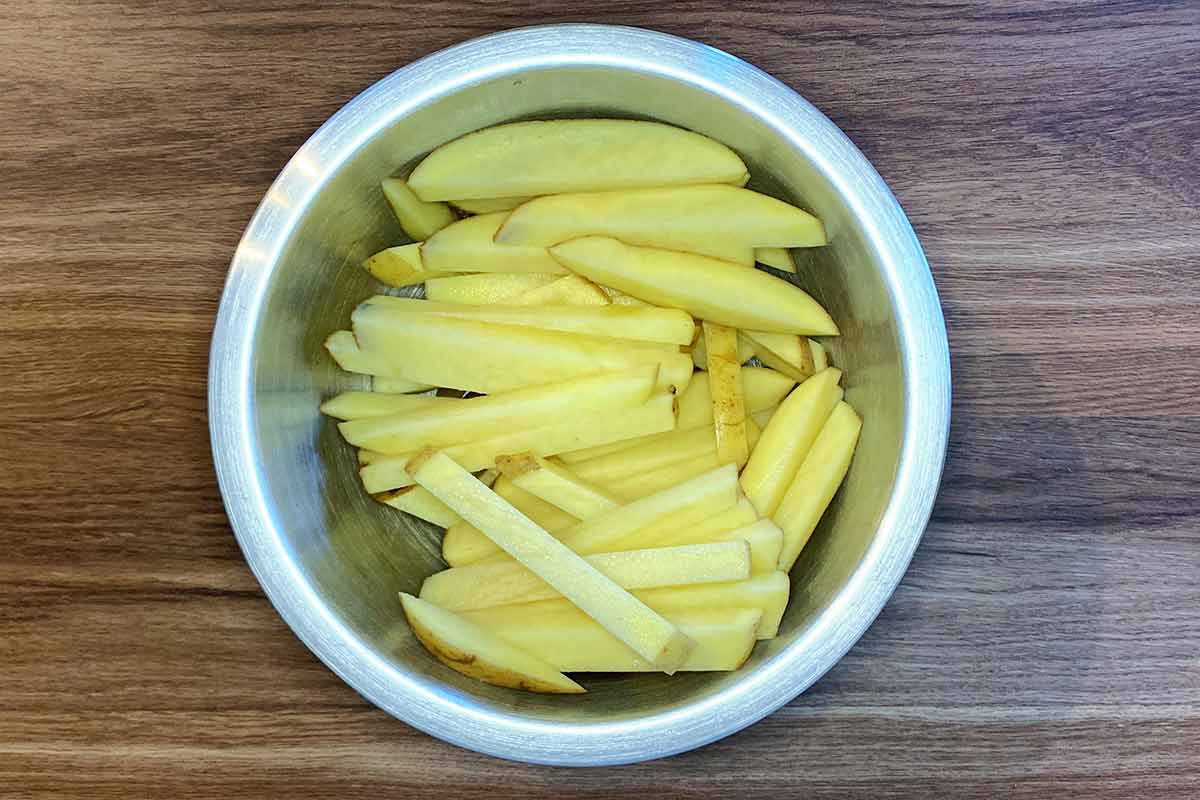 A metal mixing bowl full of uncooked chips.
