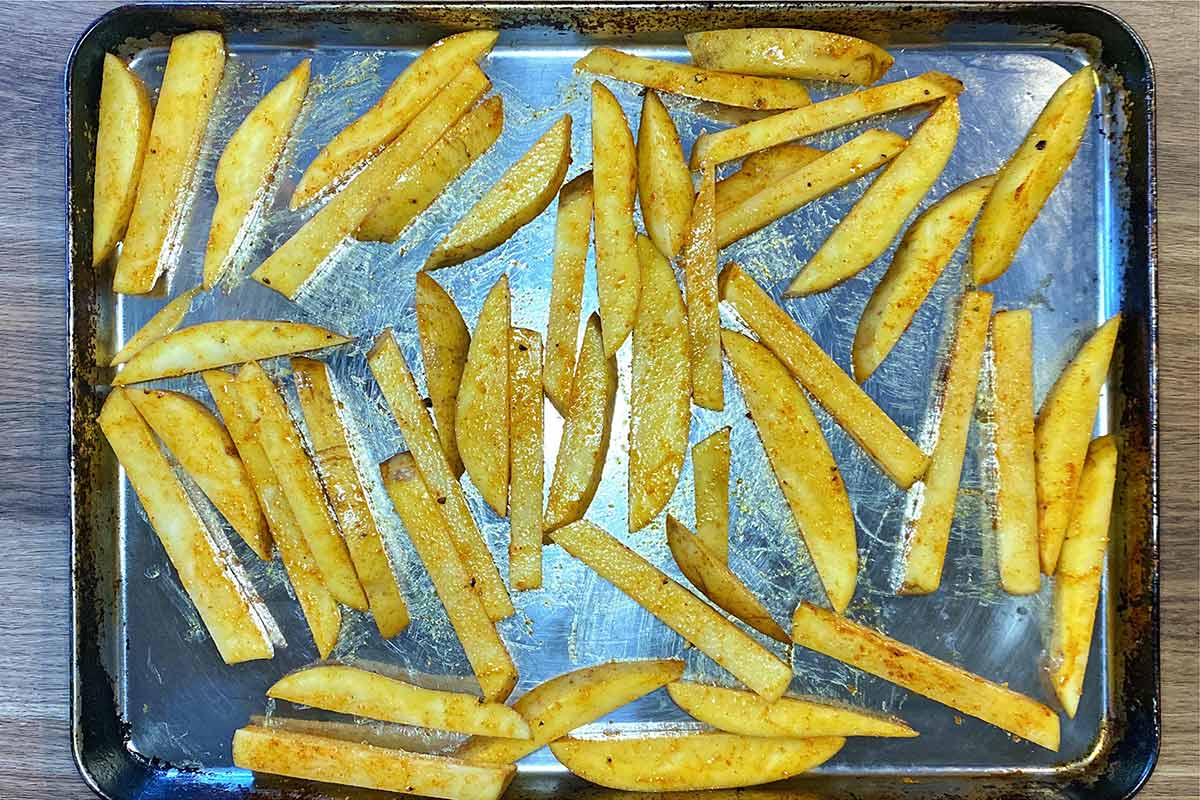 The seasoned chips spread over a large baking tray.