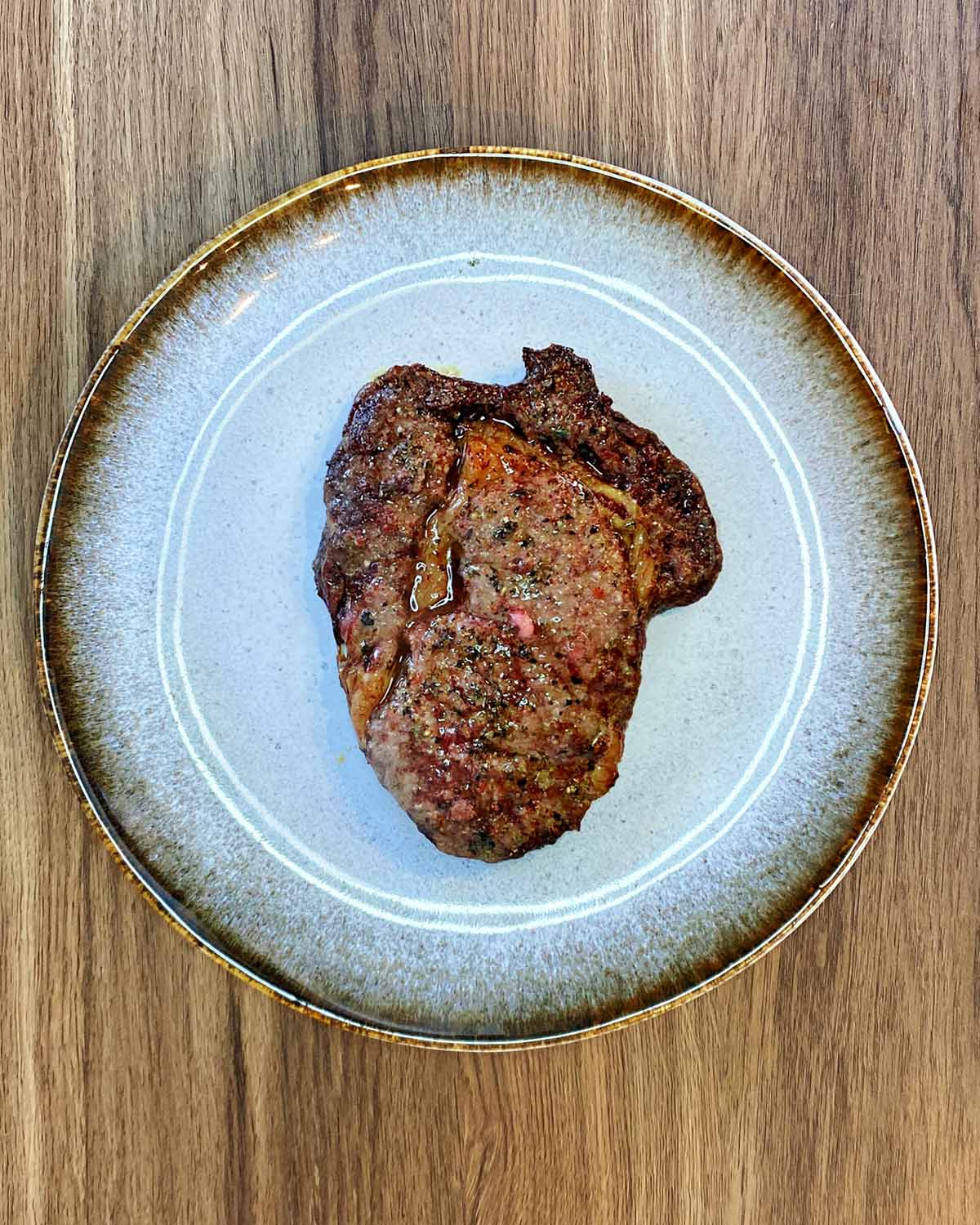 A cooked steak on a blue plate.