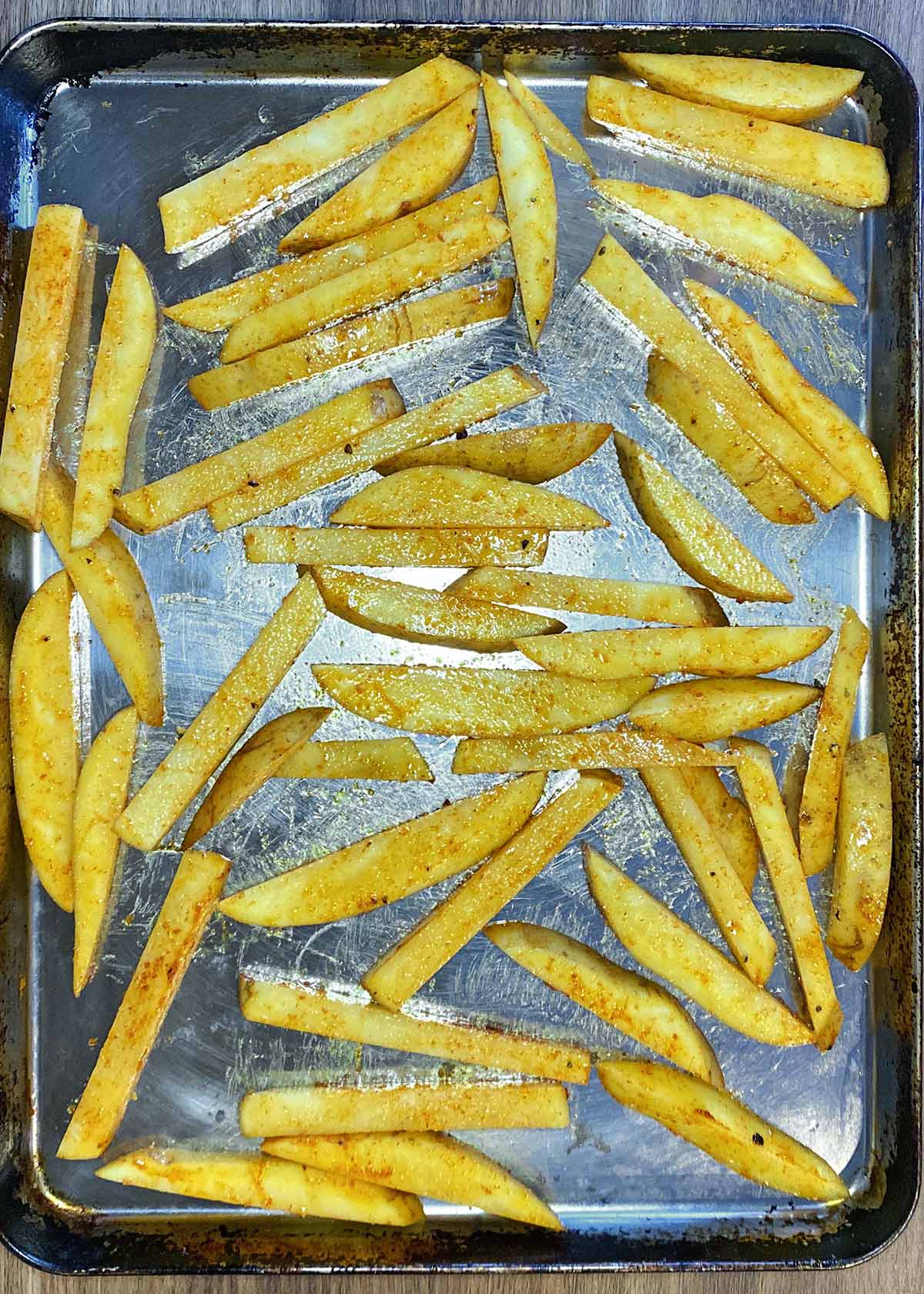 The seasoned chips spread over a large baking tray.