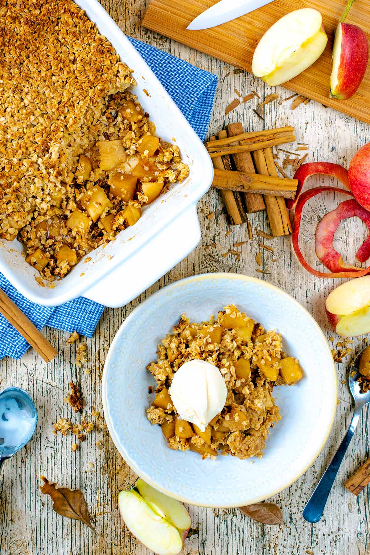 A bowl of Apple Crumble surrounded by ingredients and a baking dish.