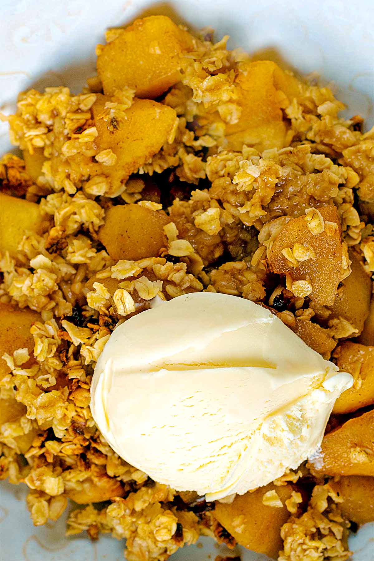 A ball of vanilla ice cream sat on top of some apple crumble.