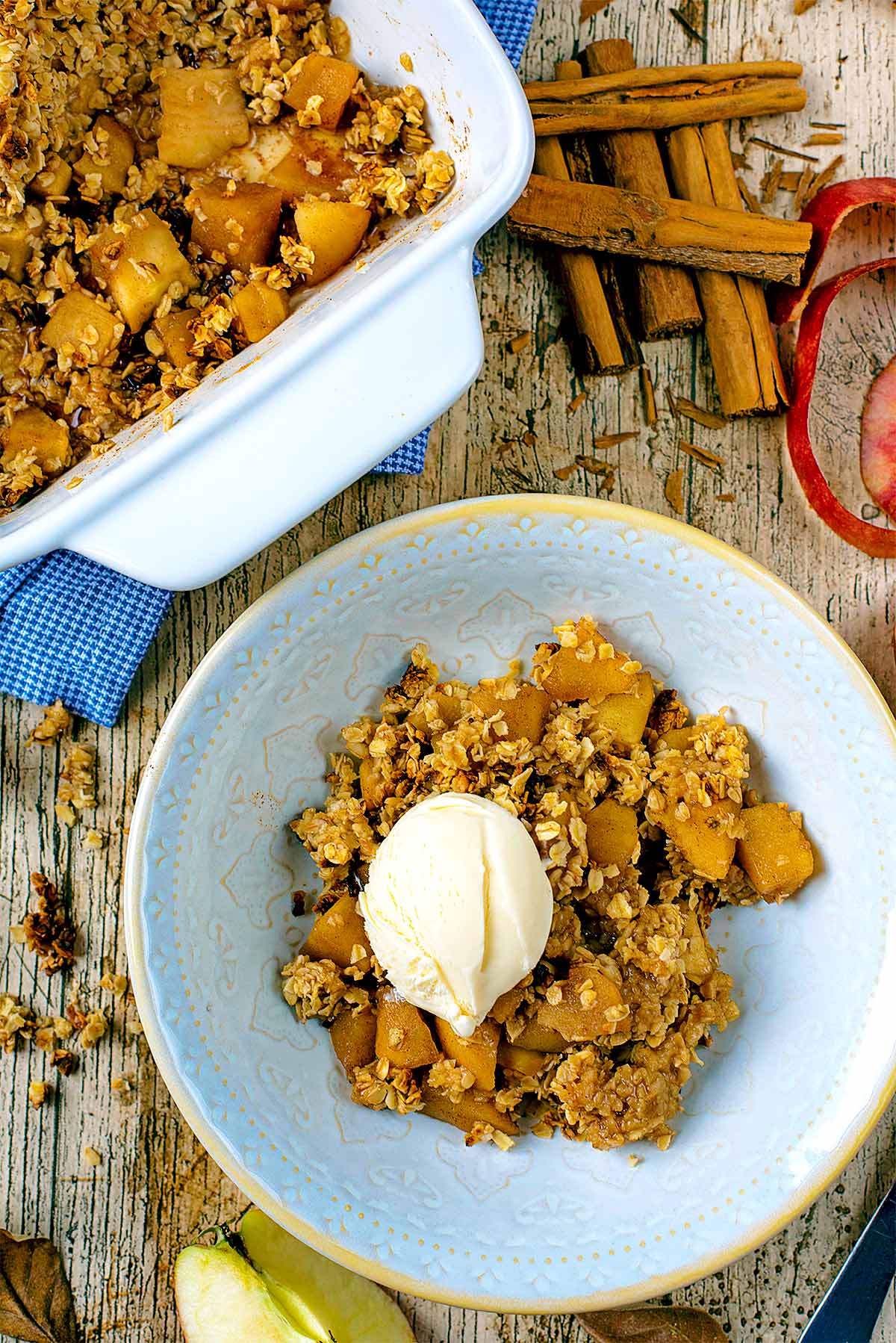 A bowl of apple crumble topped wit ha ball of vanilla ice cream.