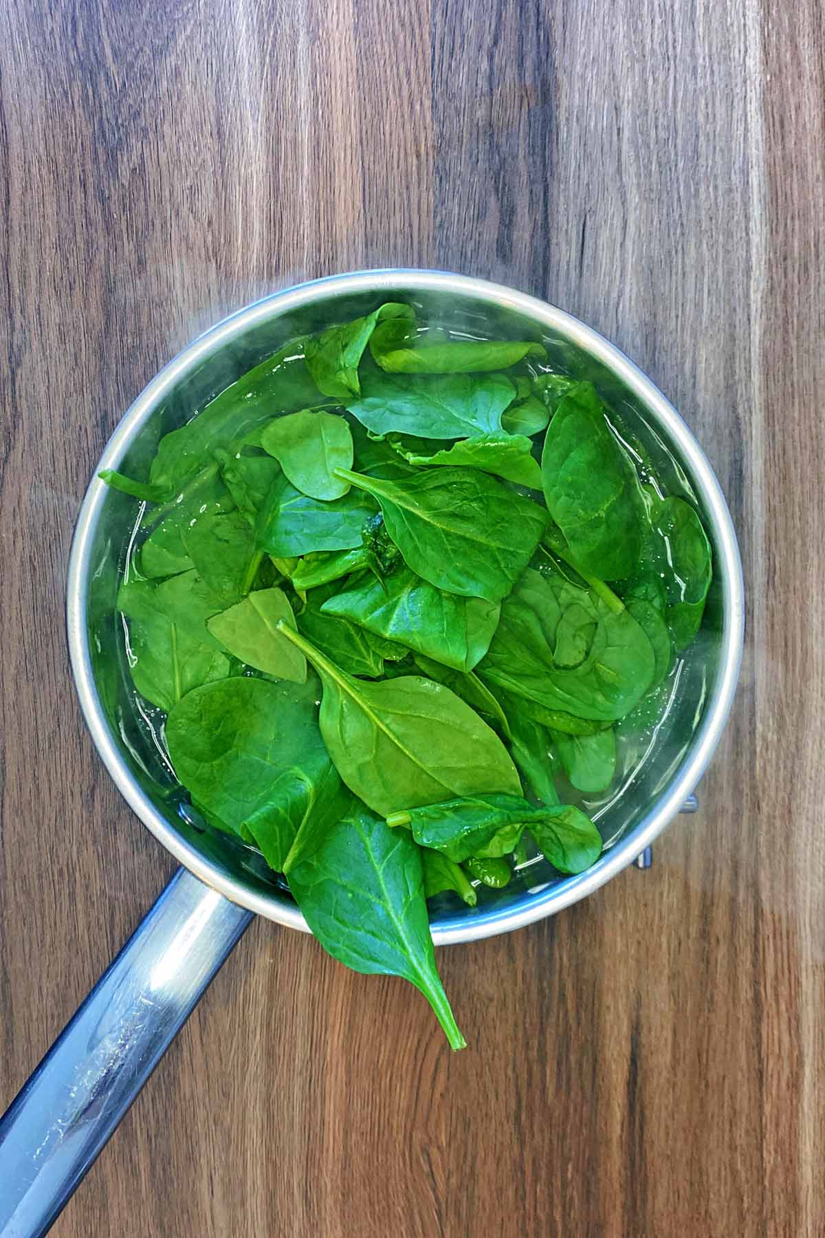 Spinach leaves added to the pan of spaghetti.