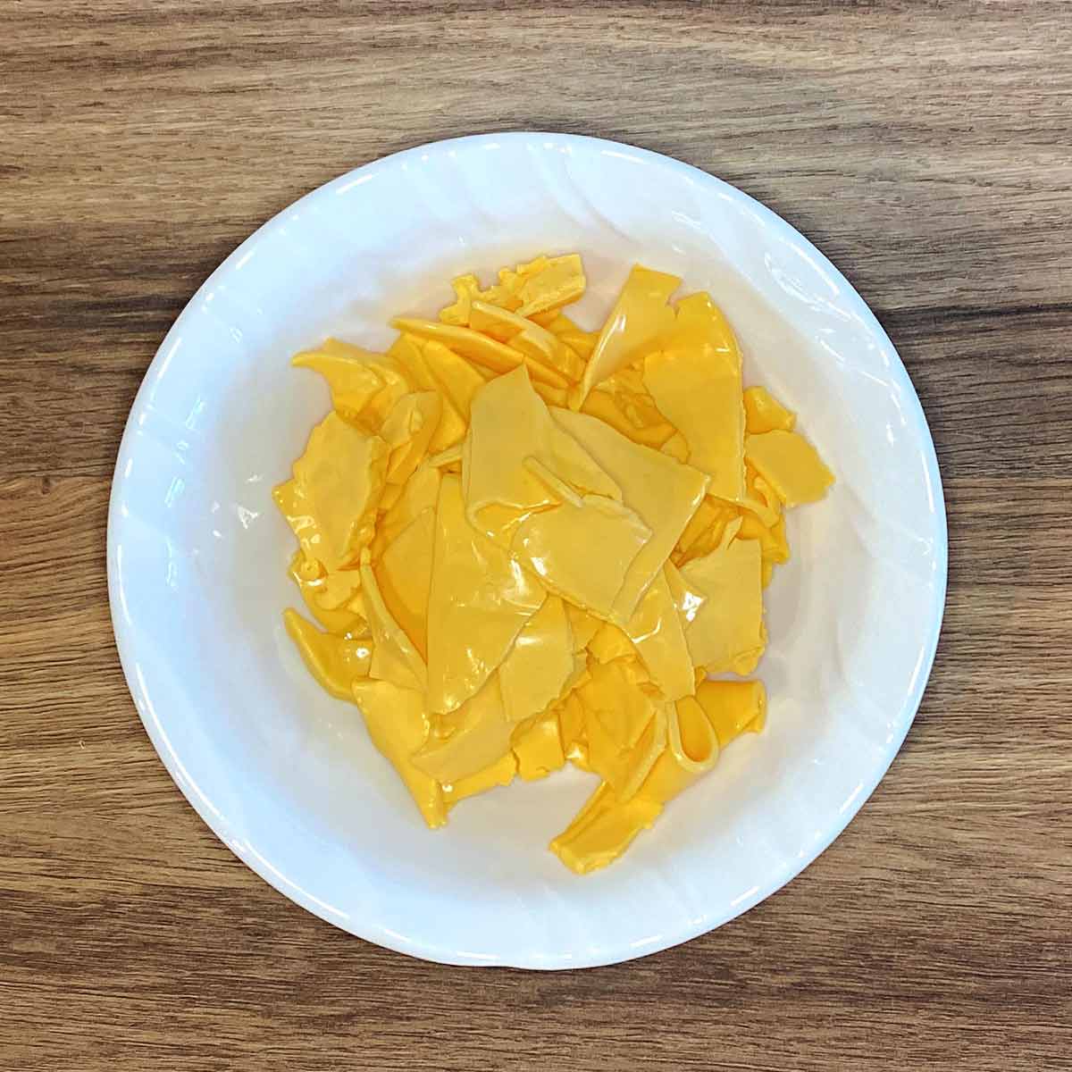 Shredded cheese slices in a white bowl.