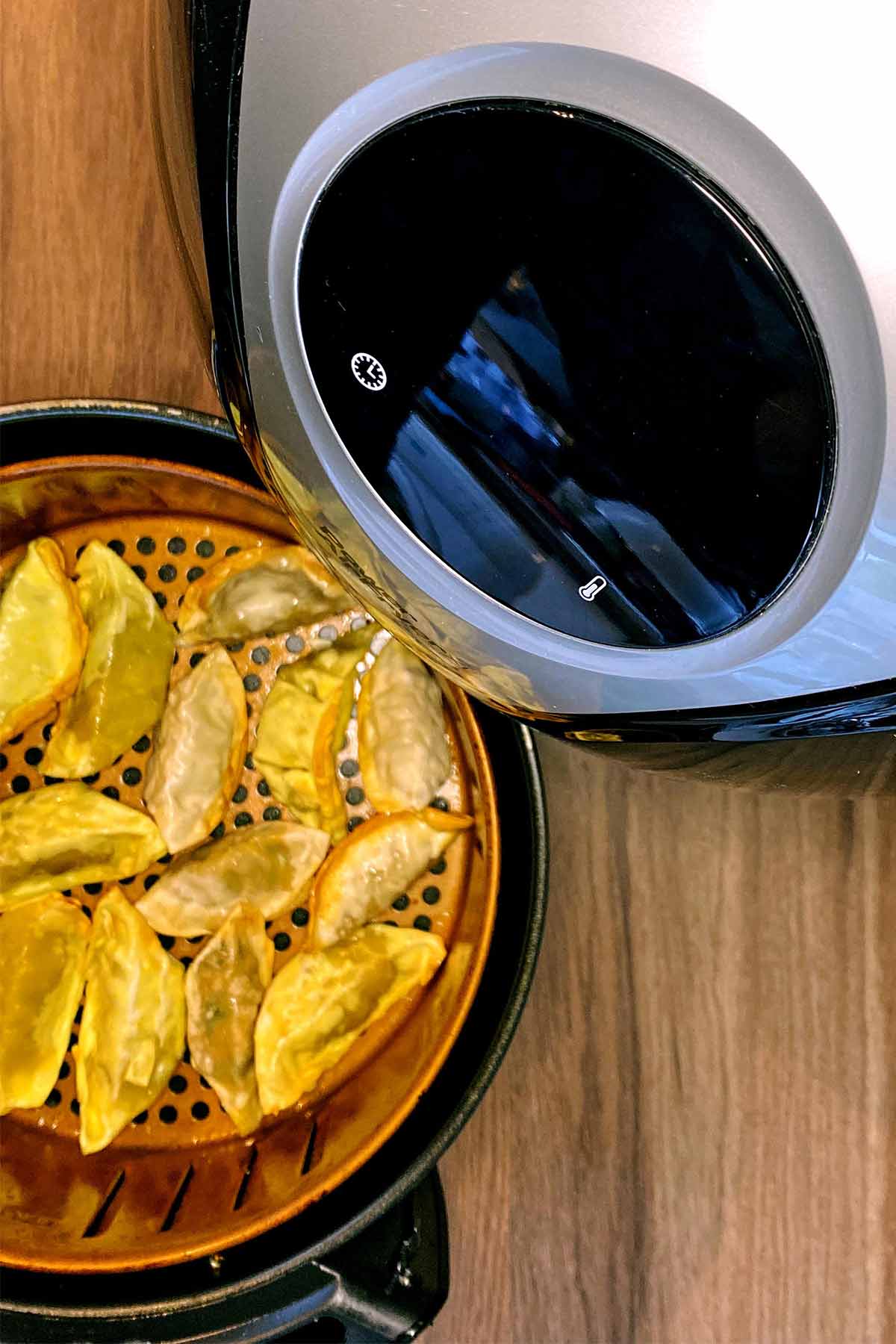 Cooked gyoza in an air fryer basket.
