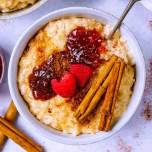Creamy rice pudding topped with jam, raspberries and cinnamon.