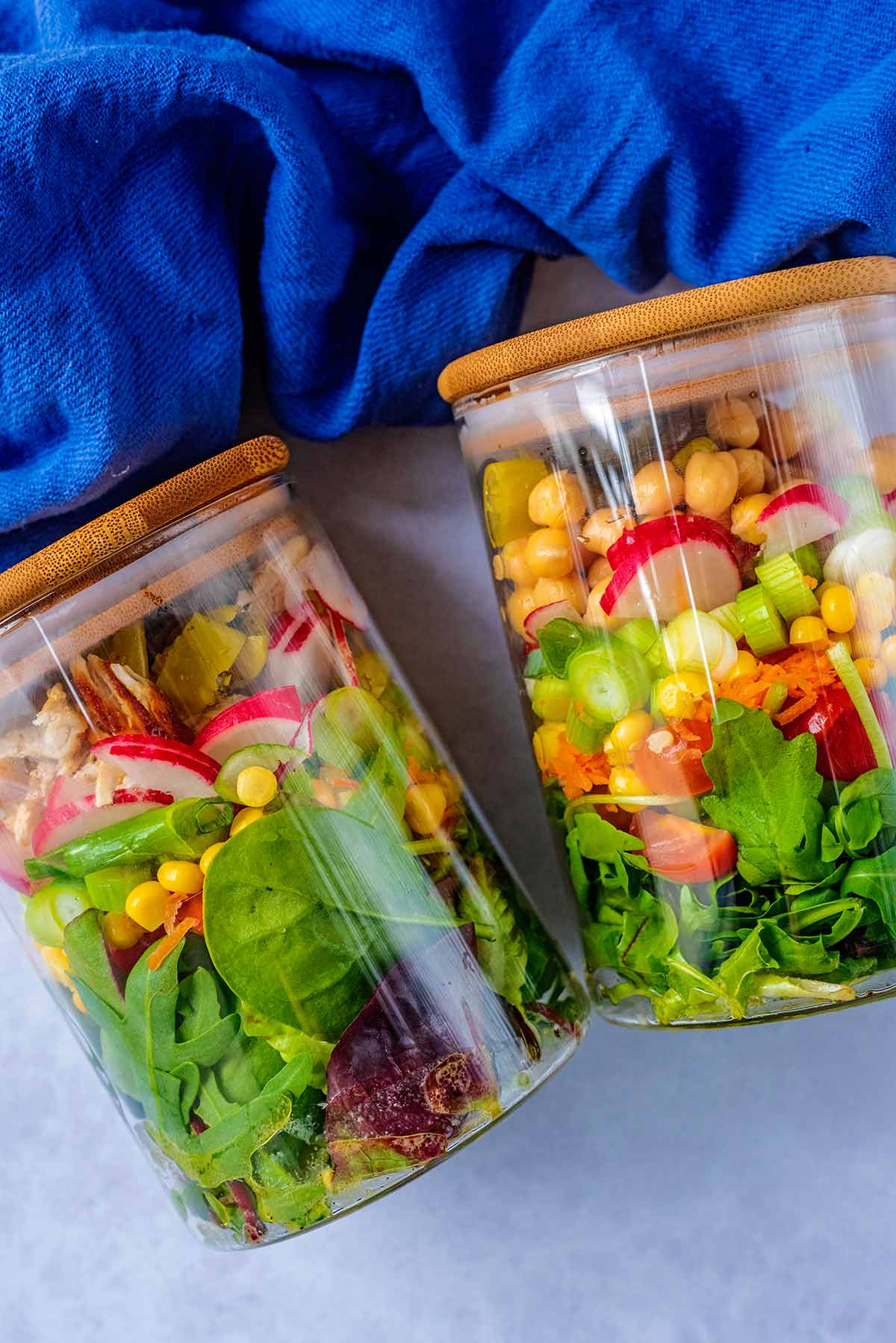 Two jars, full of salad, with lids on.