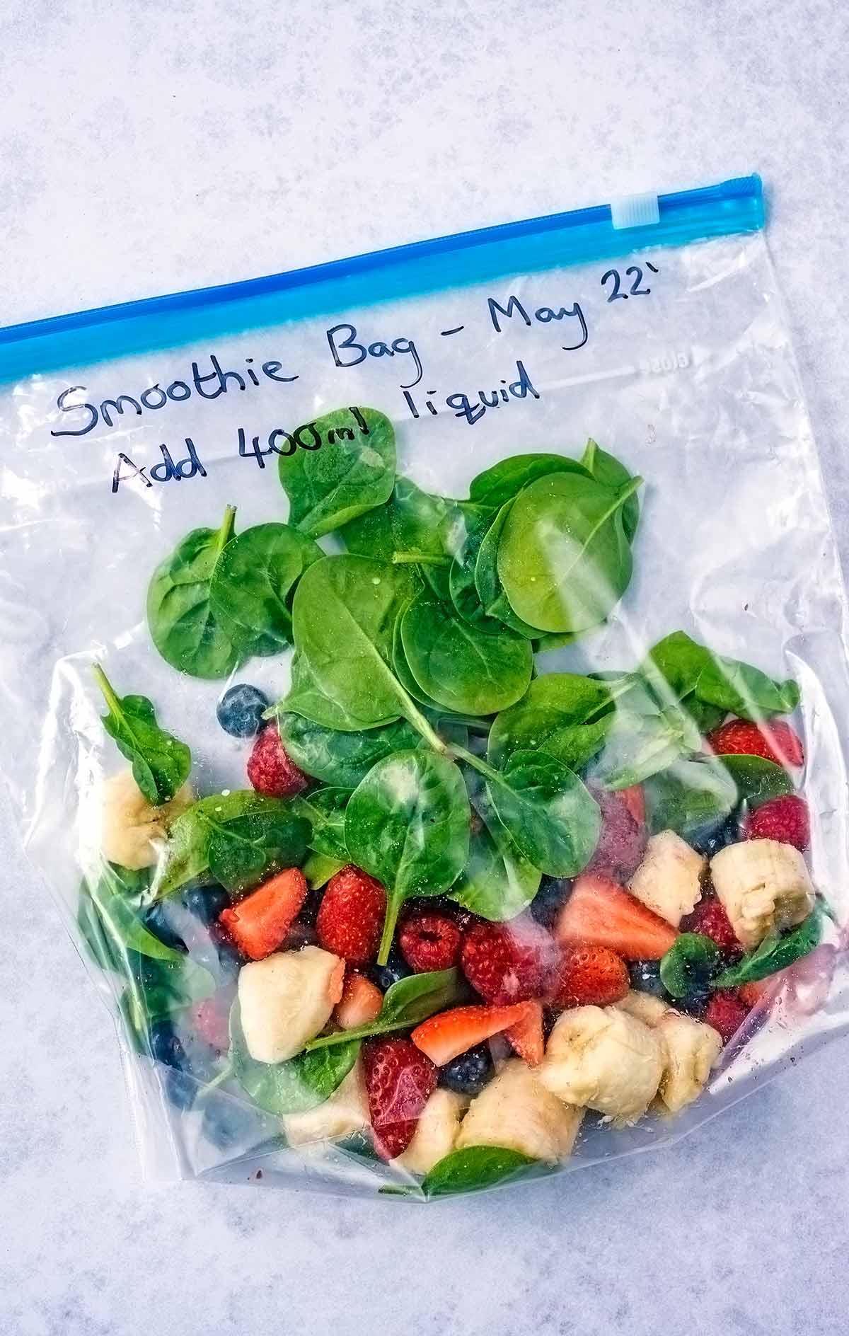Banana, spinach and berries in a labeled ziploc bag.