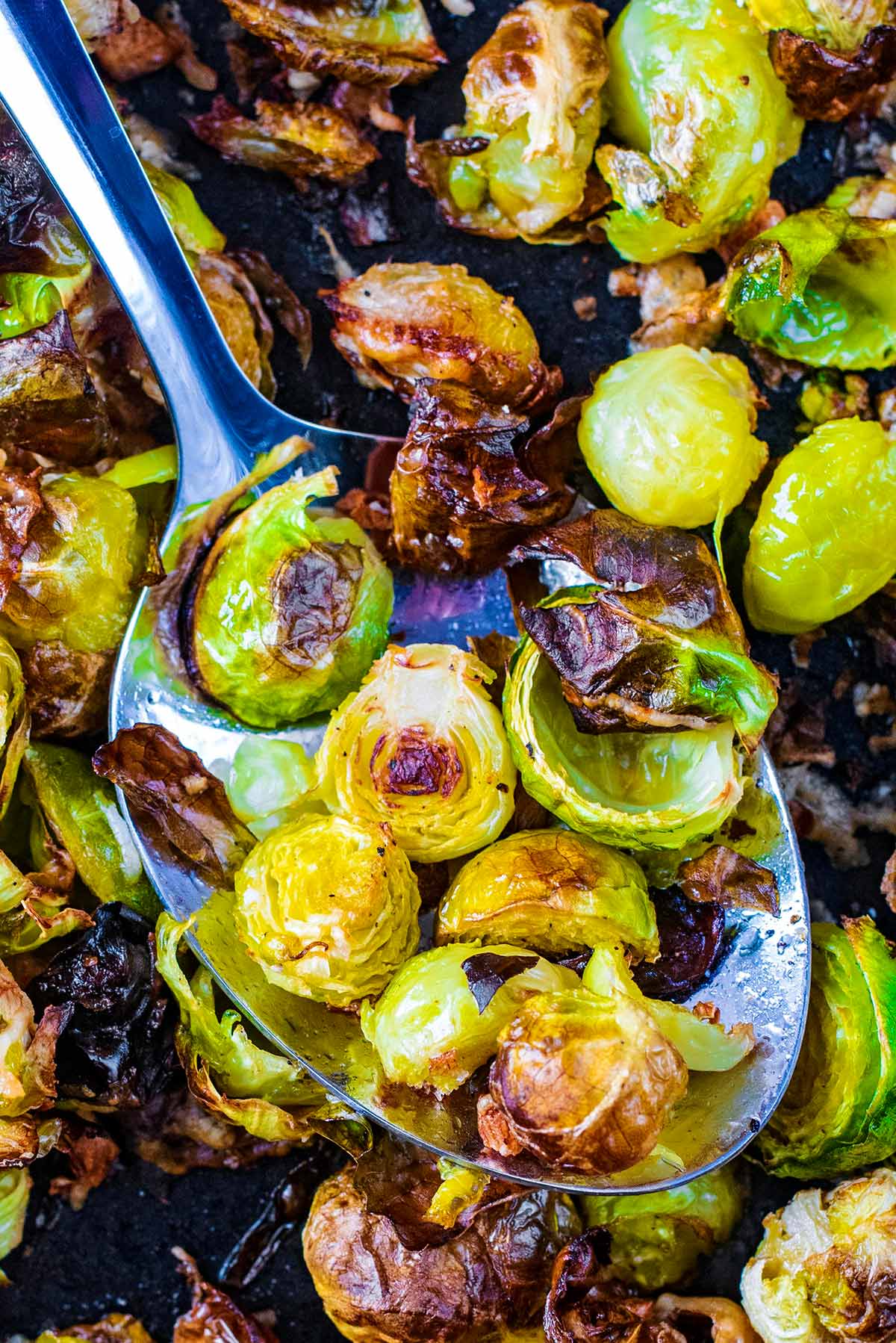 A spoon lifting up some roasted Brussels sprouts.