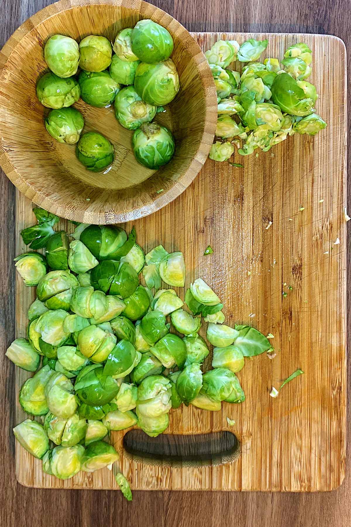 A wooden chopping board with chopped Brussels sprouts on it.