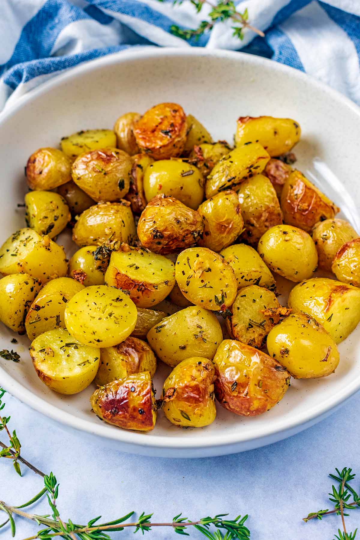 A bowl of roast potatoes in front of a striped towel.