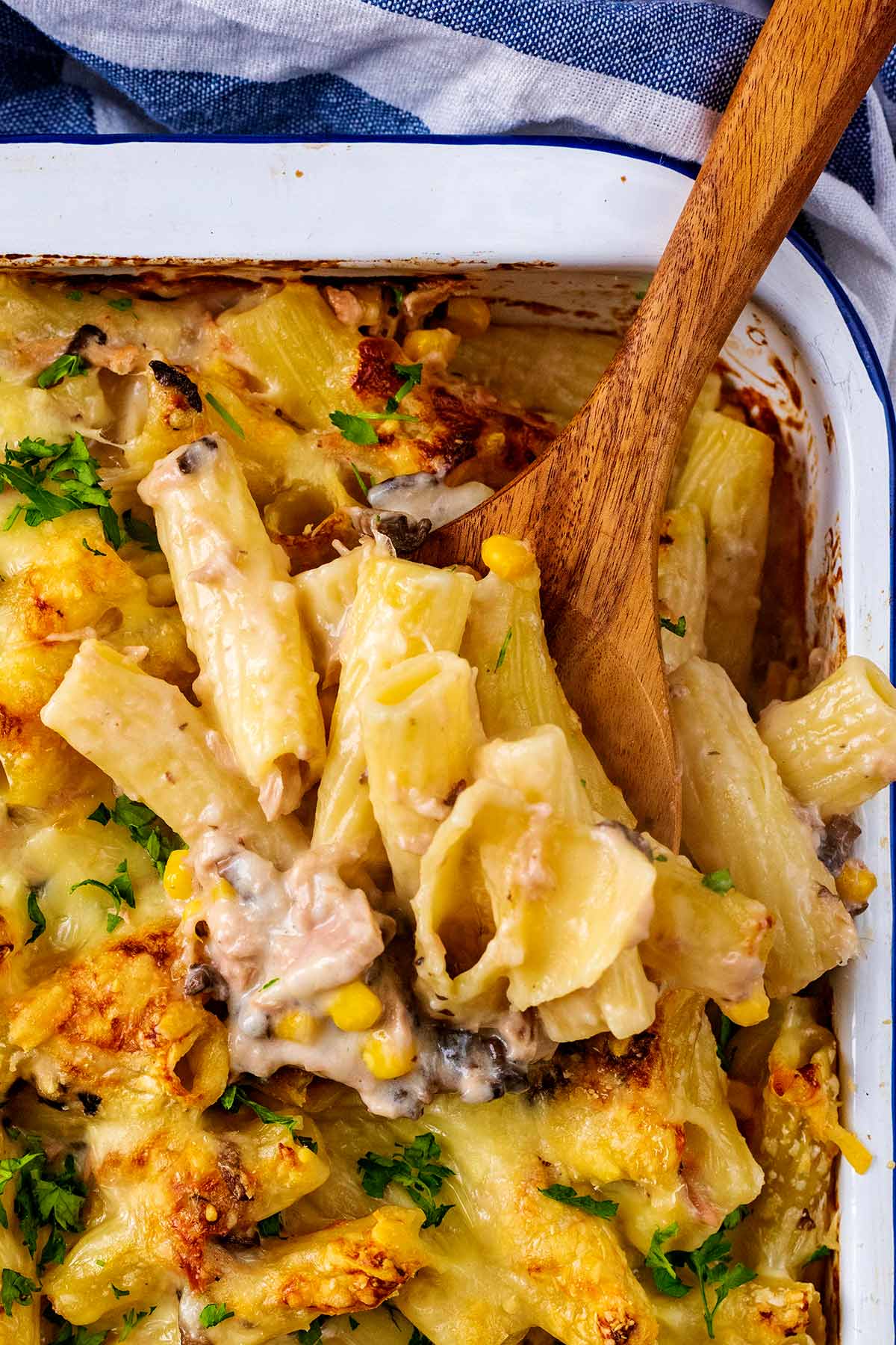 A wooden spoon in a portion of pasta bake.