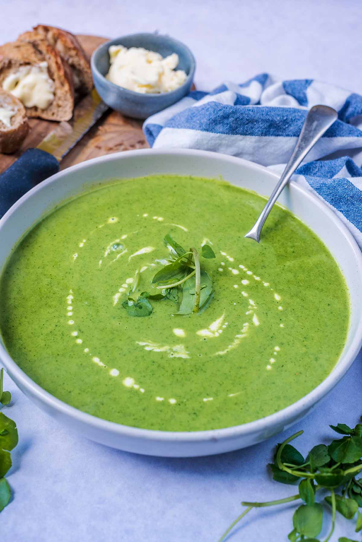 A bowl of soup in front of some bread and butter.