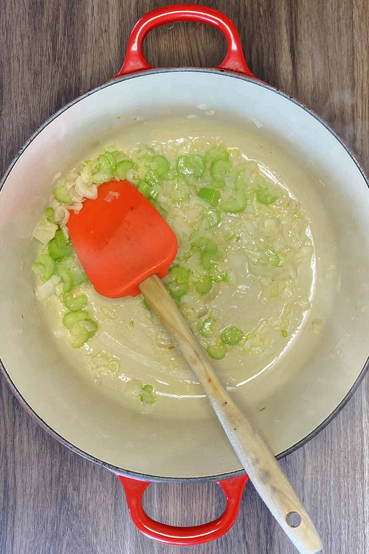 Chopped shallots and celery cooking in large pan.