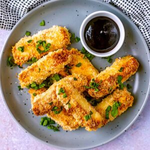 A plate of halloumi fries with a pot of bbq sauce.