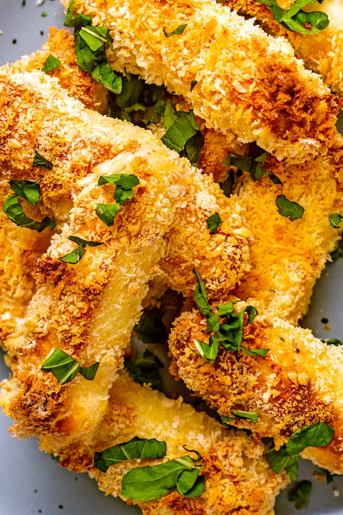 Baked halloumi fries with chopped herbs sprinkled on them.