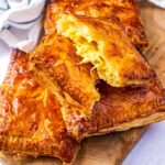 A pile of Cheese and Onion Pasties, one is brokin open.