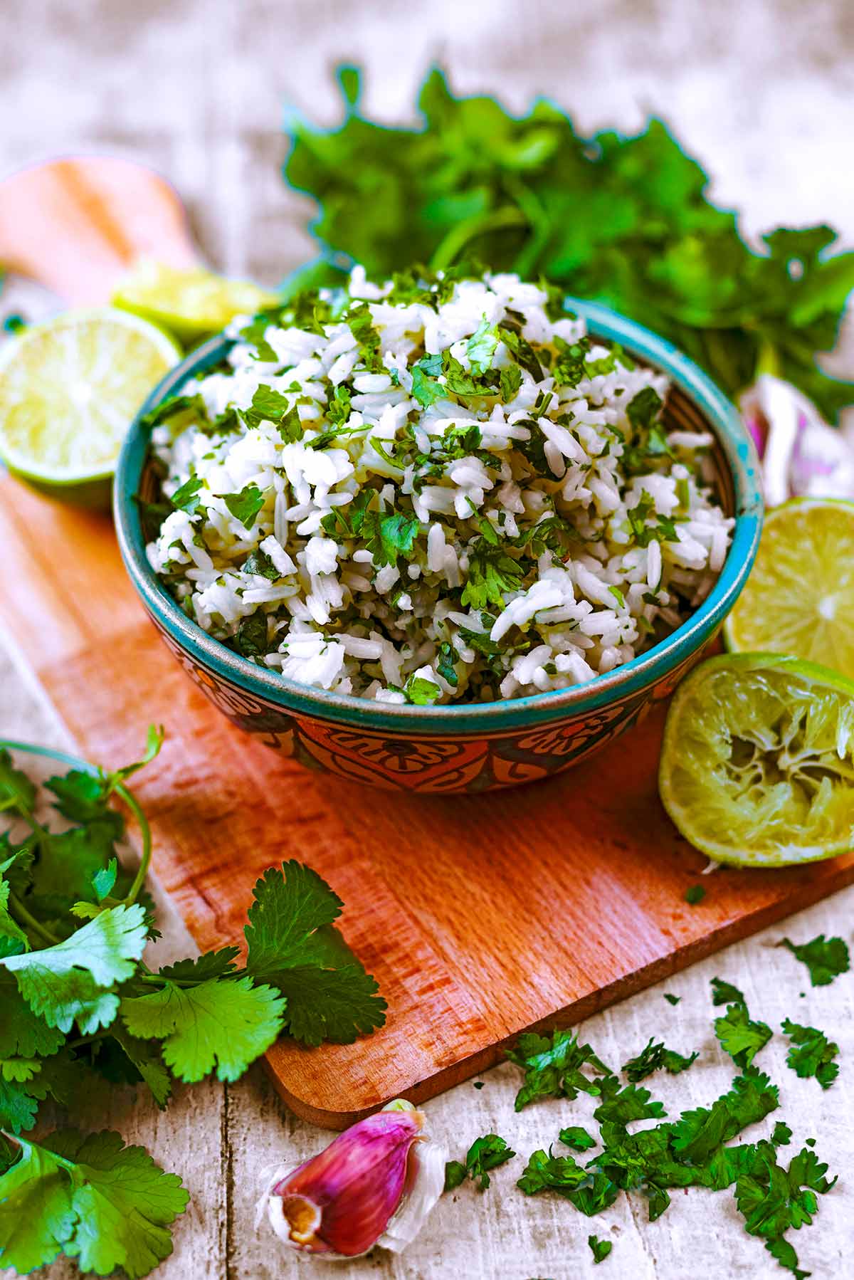 A bowl of rice topped with chopped cilantro sat on a wooden board.