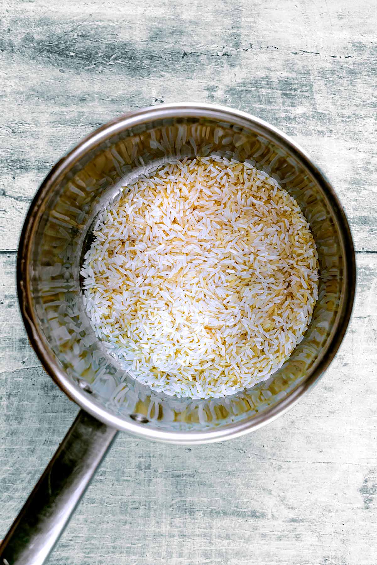 A saucepan with uncooked rice in it.