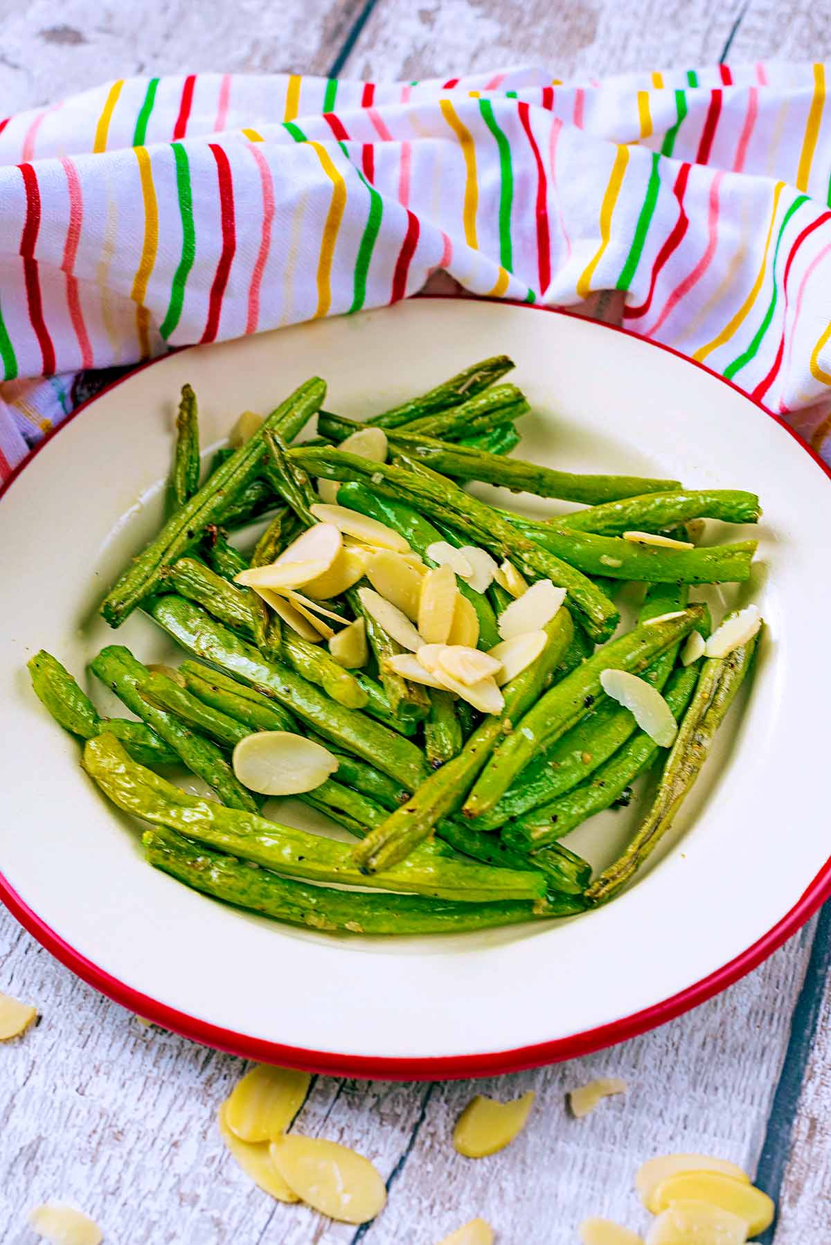 A white plate with a red trim with beans and almonds on it.