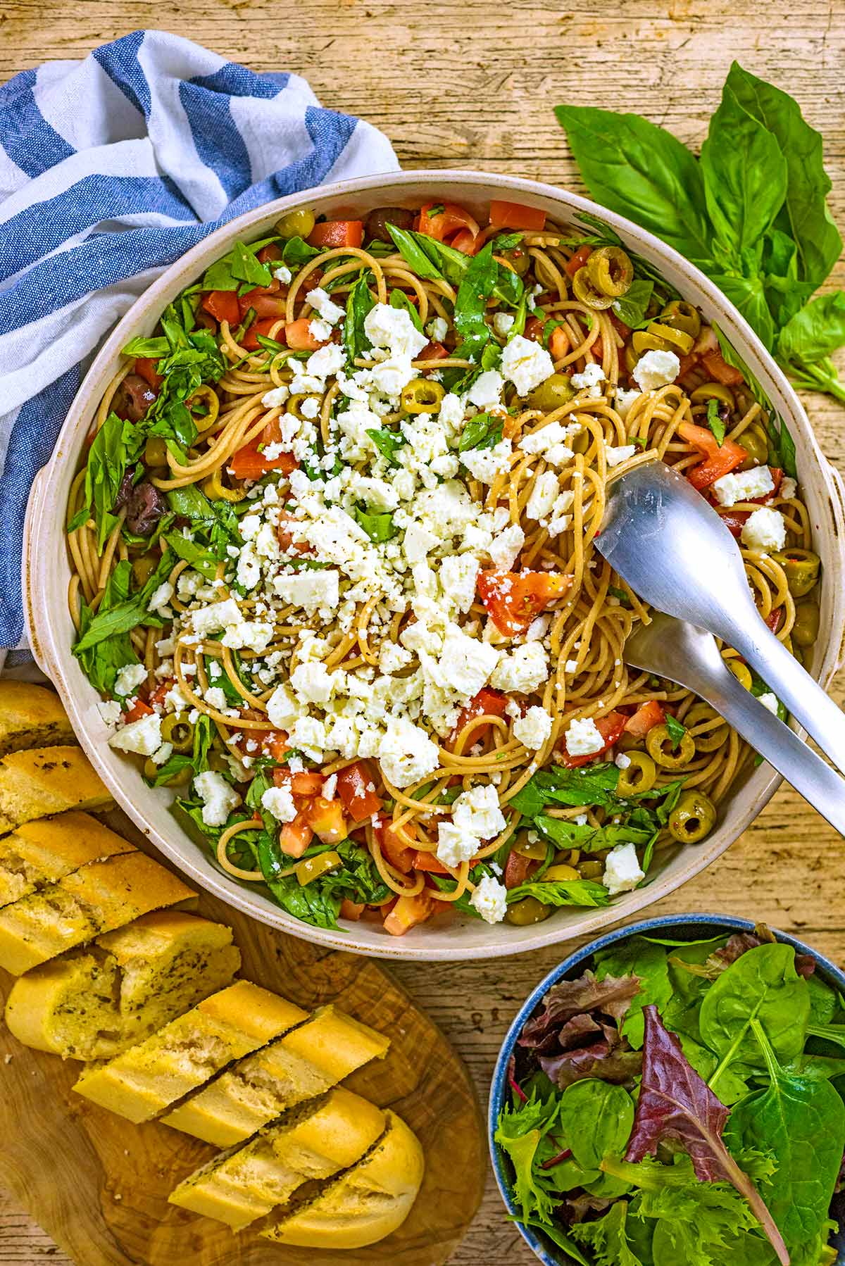 A large bowl of spaghetti and vegetables topped with crumbled feta.