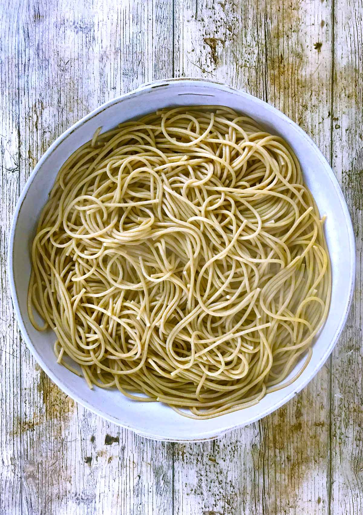 A large serving bowl full of cooked spaghetti.