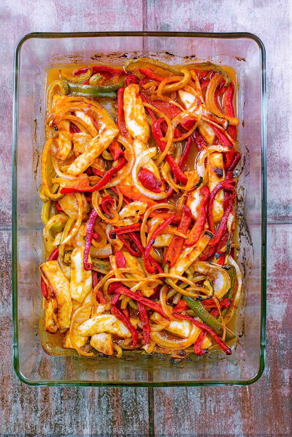 Cooked peppers, onions and halloumi in a baking dish.
