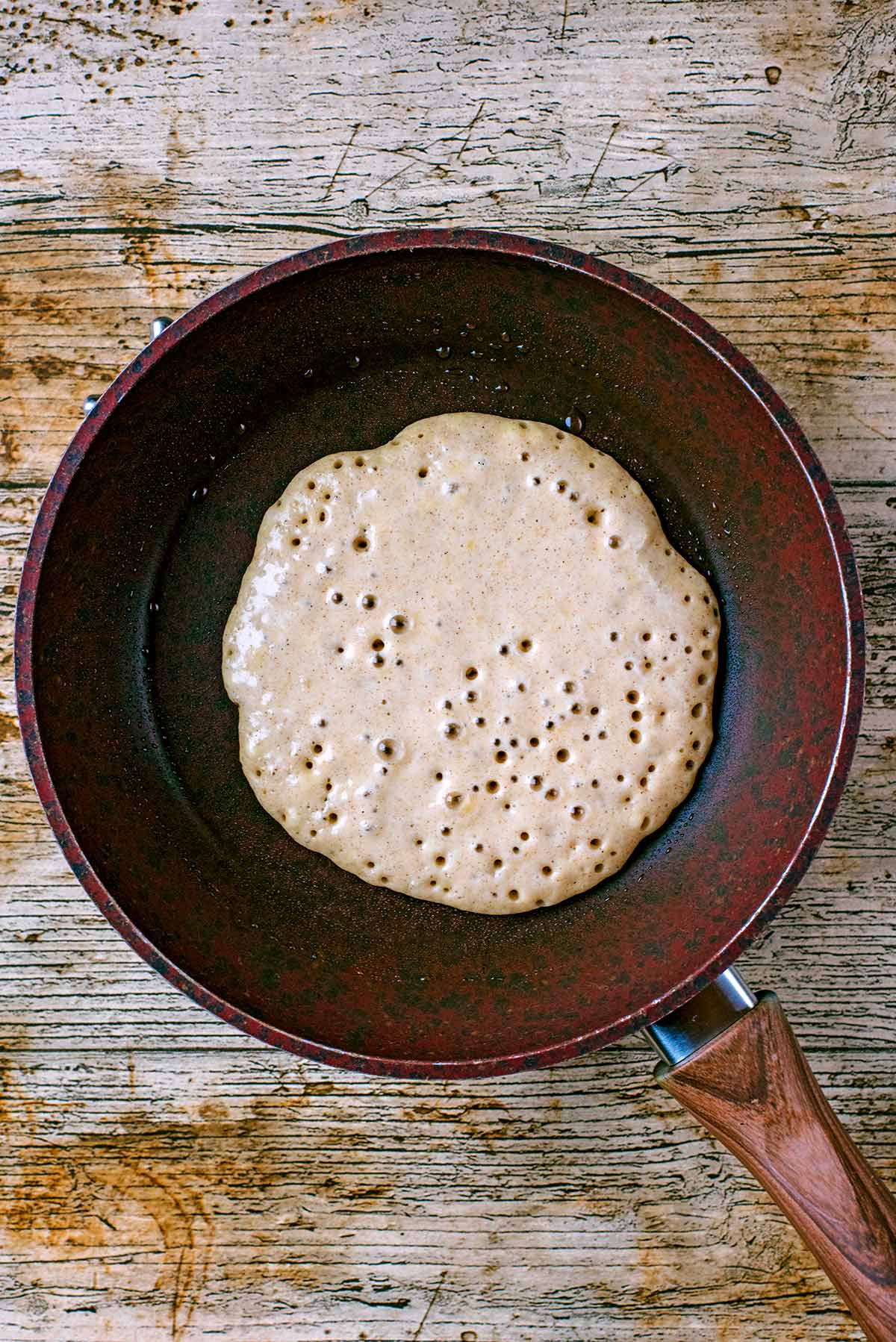 Pancake batter bubbling in a frying pan.