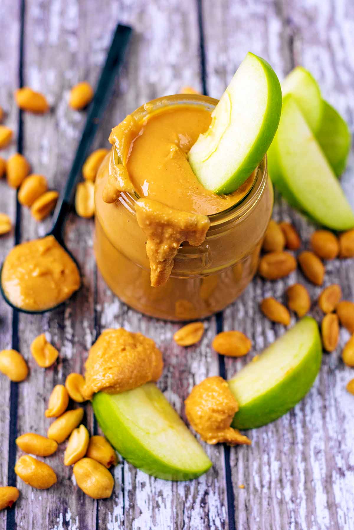 A jar of peanut butter with an apple slice dipped into it.