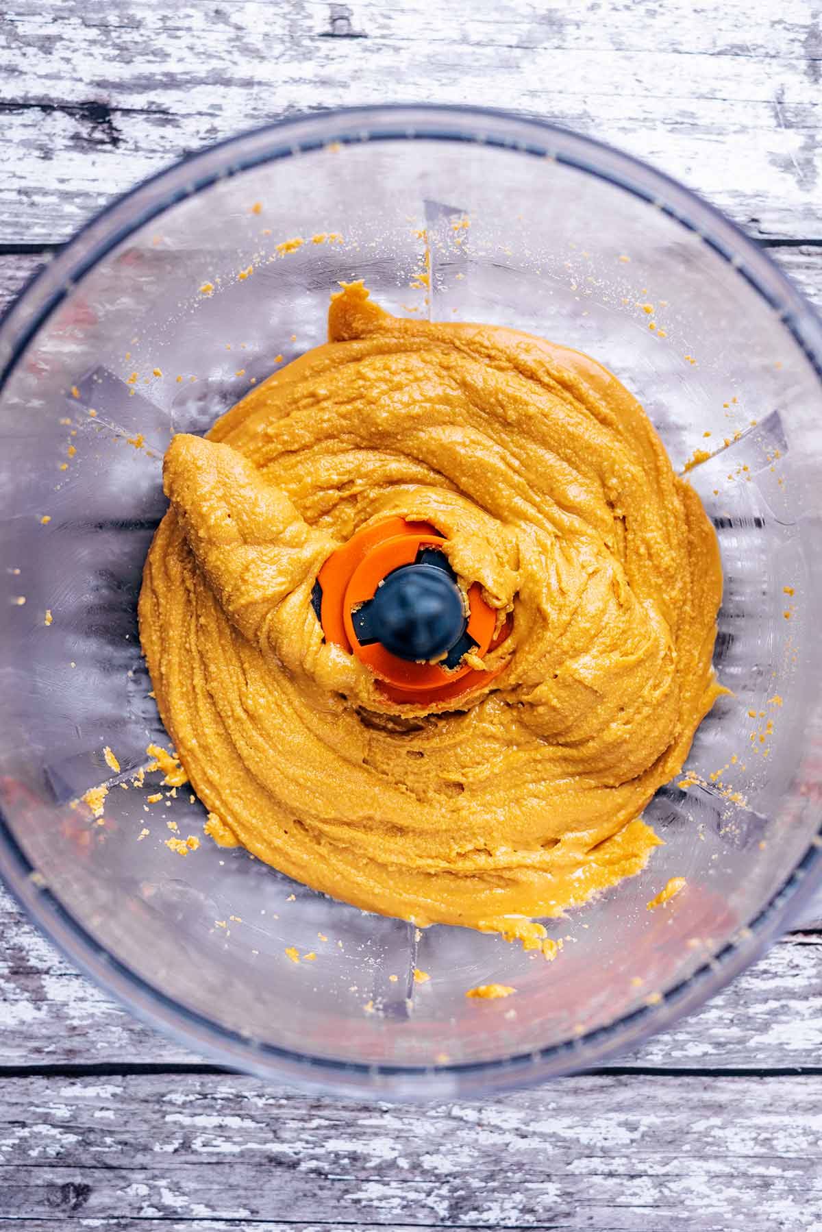 A food processor bowl containing peanut butter.