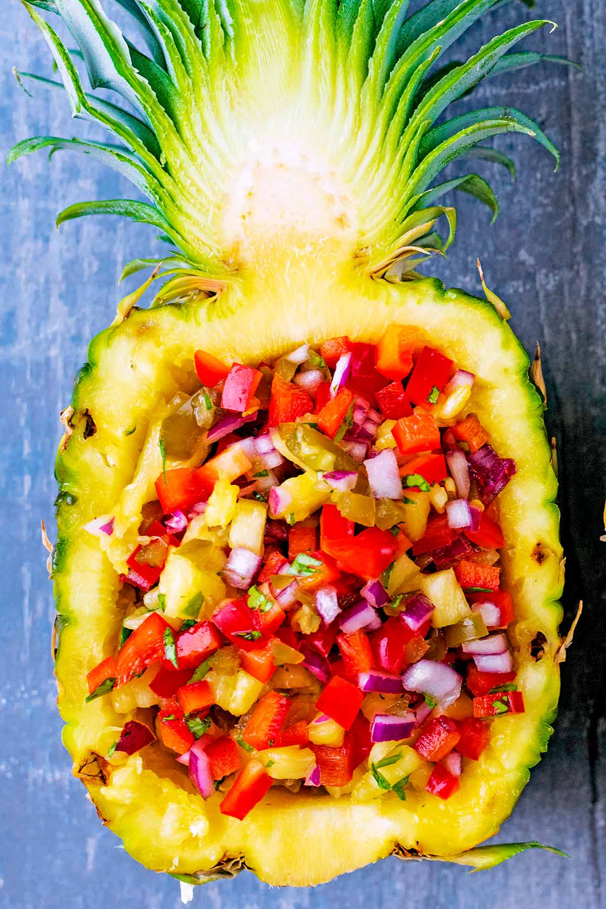A pineapple half filled with salsa.