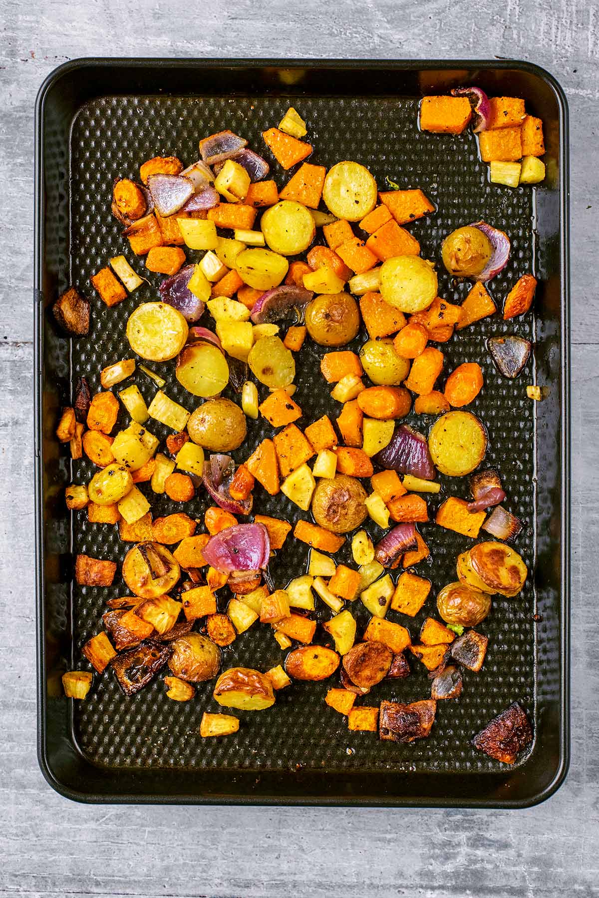 A baking tray with cooked chopped vegetables covering it.