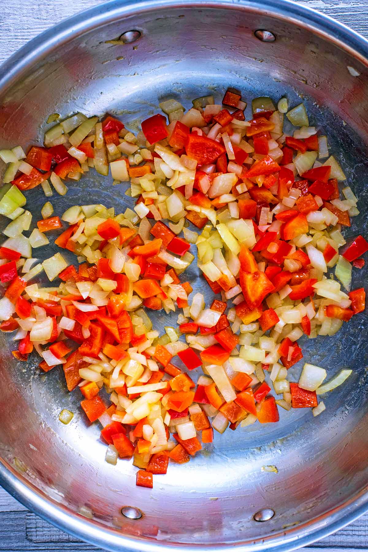 a large silver pan with chopped onion and red pepper.